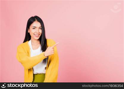 Asian happy portrait beautiful cute young woman standing makes gesture one fingers point upwards above presenting product something, studio shot isolated on pink background with copy space