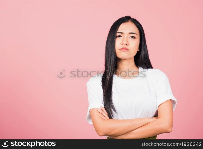 Asian happy portrait beautiful cute young woman standing with crossed arms angry and mad raising fist frustrated and furious while shouting with anger isolated, studio shot on pink background