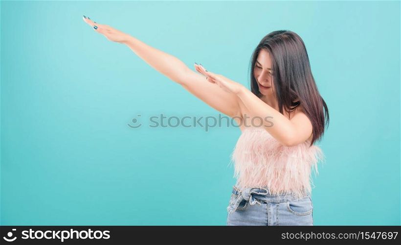 Asian happy portrait beautiful young woman standing smiling exercise Showing DAB dance gesture and looking to side isolated on blue background with copy space for text