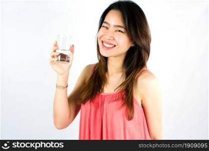 Asian healthy woman smiling with happiness, drinking and holding a glass of water while standing on white background