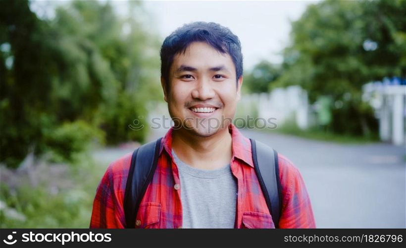Asian hiker man trekking in forest. Young happy backpack male smiling to camera, travel nature and adventure trip, climb mountain lot of tree in spring holidays vacation concept.