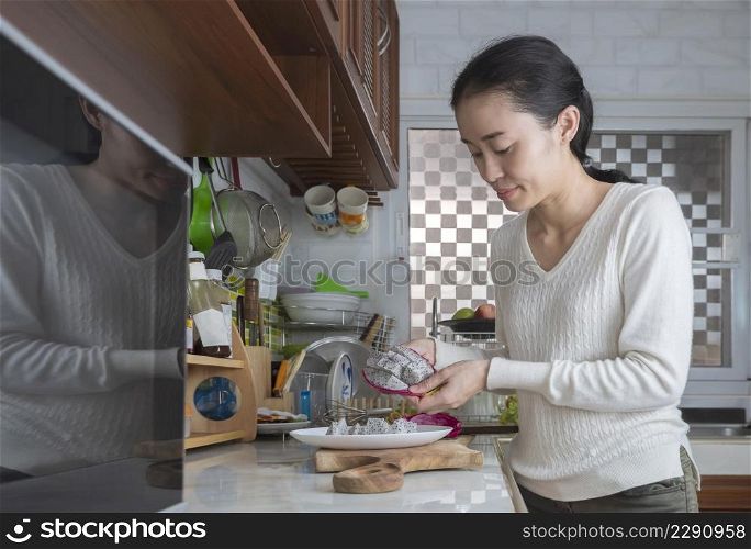 Asian housewife is preparing dragon fruit or Pitaya on counter in the kitchen at home