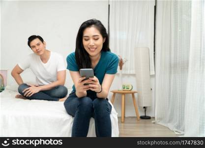 Asian husband feeling suspicious of my wife’s abnormality in smartphone use and his wife ignores him and uses the smartphone all time. Concept of relationship problem and Infidelity