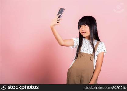 Asian kid 10 years enjoying using mobile phone take selfie at studio shot isolated on pink background, Happy child girl lifestyle using smartphone making video selfie