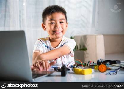 Asian kid boy learns coding and programming with laptop for Arduino robot car, Little child students typing code in computer online with car toy, STEAM education AI technology future course learning