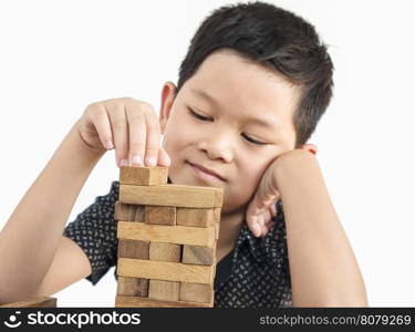 Asian kid is playing jenga, a wood blocks tower game for practicing physical and mental skill