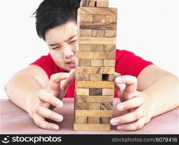 Asian kid is playing wood blocks tower game for practicing physical and mental skill. Photo is focused at model hands and isolated over white.