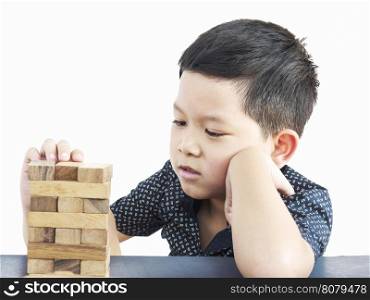 Asian kid is playing wood blocks tower game for practicing physical and mental skill. Photo is isolated over white.