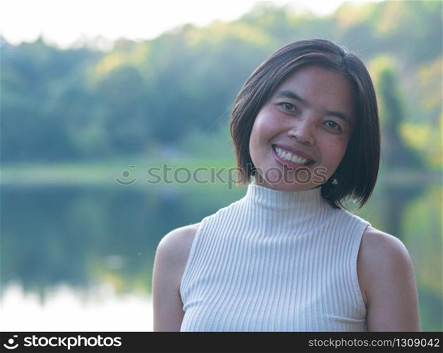Asian lady smiling at beautiful lake in the morning