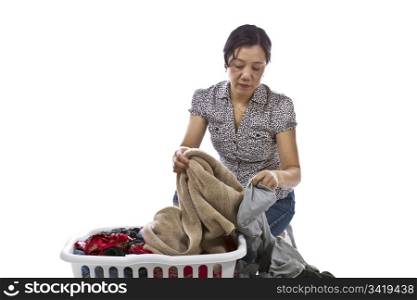 Asian lady sorting laundry in basket while wearing causal clothing on white background