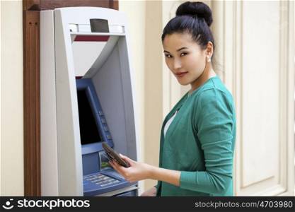 Asian lady using an automated teller machine . Woman withdrawing money or checking account balance