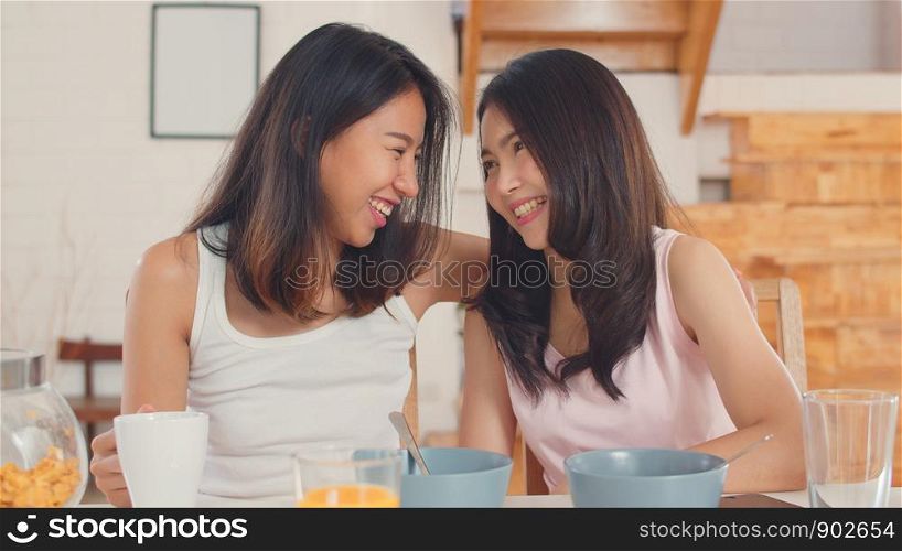 Asian Lesbian lgbtq women couple have breakfast at home, Young Asia lover female feeling happy drink juice, corn flakes cereal and milk in bowl on table in kitchen in the morning concept.