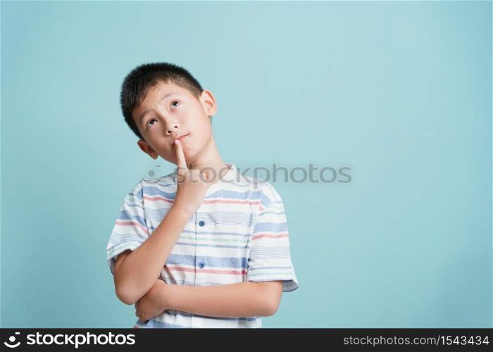 Asian little boy standing thinking on blue background isolated, Asia man look up and copy space