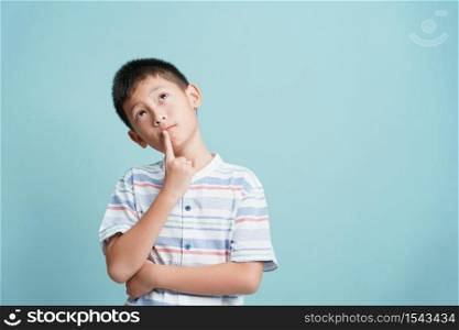 Asian little boy standing thinking on blue background isolated, Asia man look up and copy space