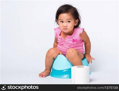 Asian little cute baby child girl education training to sitting on blue chamber pot or potty with toilet paper rolls, studio shot isolated on white background, wc toilet concept