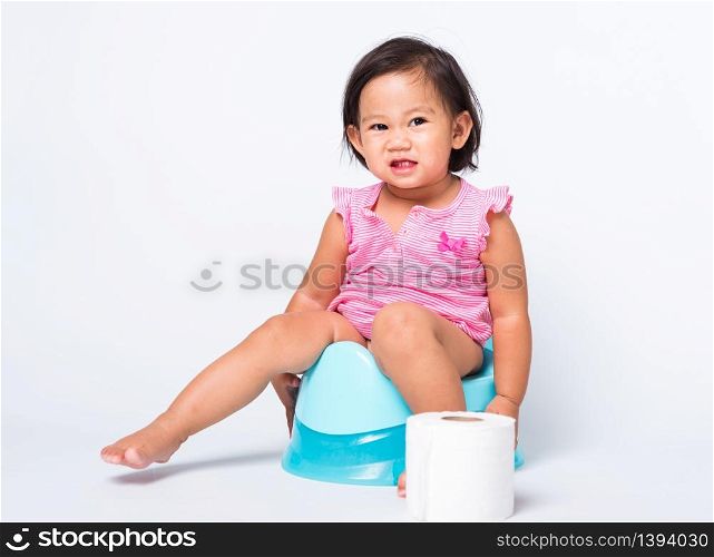 Asian little cute baby child girl education training to sitting on blue chamber pot or potty with toilet paper rolls, studio shot isolated on white background, wc toilet concept