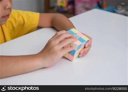 Asian little cute girl holding Rubik&rsquo;s cube in her hands and playing with it. Rubik&rsquo;s cube is a game that increases intelligence for children. Educational toys for children