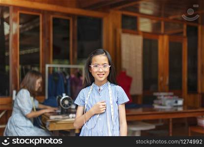 asian little girl dressmaker looking at camera with smile while standing in workshop. asian little girl dressmaker