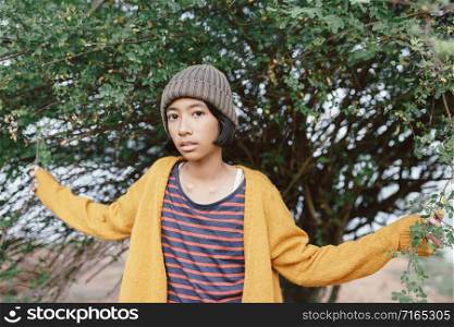 Asian little girl posing In the midst of nature in the morning. Asia woman wearing long-sleeved yellow shirt and wool hat in winter