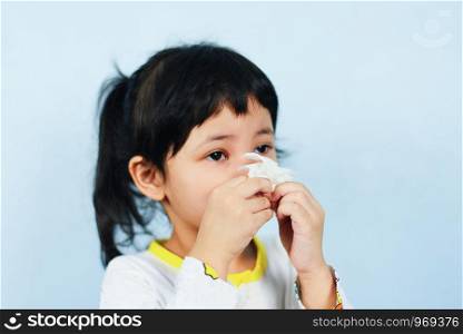 Asian little girl sick wrapped in handkerchief get cold and blow nose the flu season / child runny nose and sneezing blowing their nose and fevers at home