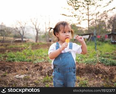 Asian little girl walking in the park and eating ice cream deliciously in summer. Cute face.