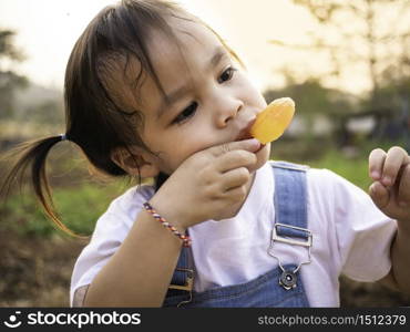 Asian little girl walking in the park and eating ice cream deliciously in summer. Cute face.