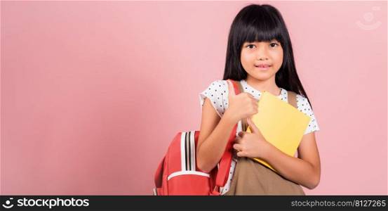 Asian little kid 10 years old with backpack is staying ready for back to school at studio shot isolated on white background, Portrait of happy child girl with school bag and holding or hugging books