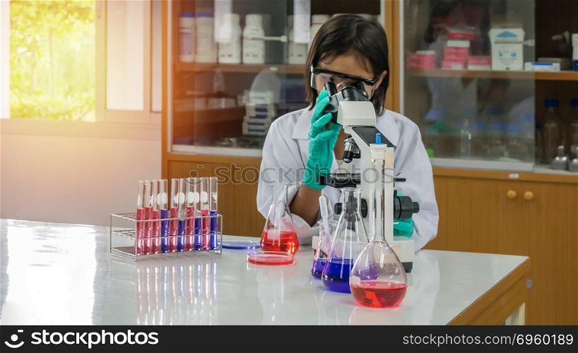 asian little scientist . asian little scientist looking through a microscope in a laboratory