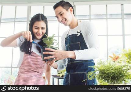 Asian lovely couple helping each other taking care plants together in indoor comfortable home. Love and Hobby Concept.