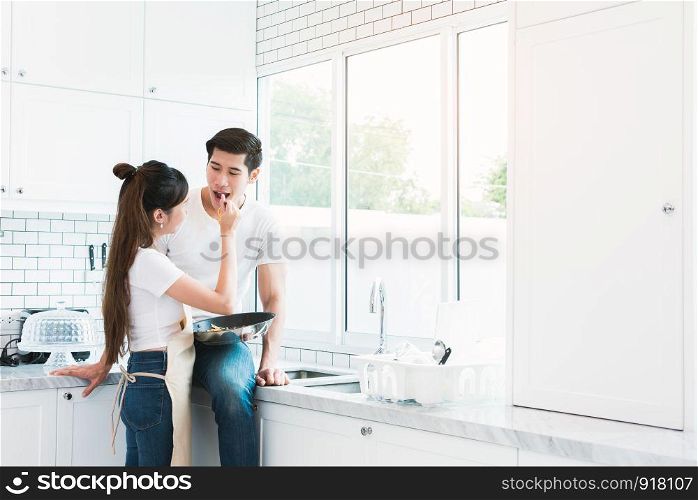 Asian Lovers feeding fruit and food to each other, Couple and Family concept. Sweet honeymoon and Holidays theme. Holiday cooking and Indoor interior