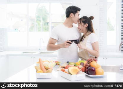 Asian lovers in kitchen, Man give forehead kiss to woman while clink wine glasses to each other. Family and Couple concept. Honeymoon and Holidays theme