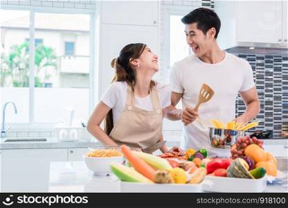Asian lovers or couples cooking so funny together in kitchen with full of ingredient on table. Honeymoon and Happiness concept. Valentines day and Sweet home