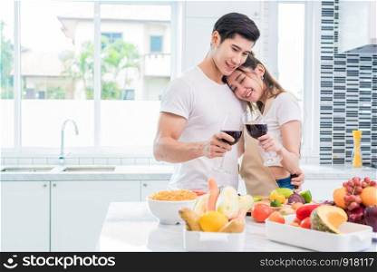 Asian lovers or couples drinking wine in kitchen room at home. Love and happiness concept Sweet honeymoon and Valentine day theme
