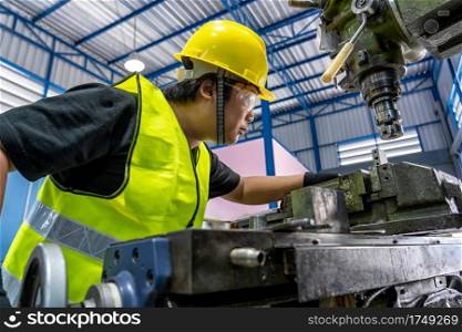 Asian machinist in safety suit operating the professional lathes in metalworking factory, lathe grinding metalworking industry concept