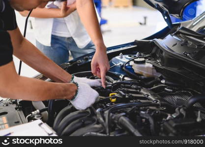 Asian male auto mechanic examine car engine breakdown problem in front of automotive vehicle car hood with female customer. Safety technical inspection care check service maintenance for road trip