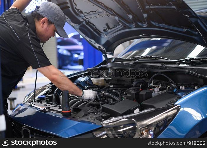 Asian male auto mechanic examine car engine breakdown problem in front of automotive vehicle car hood. Safety technical inspection care check service maintenance for customer before long road trip