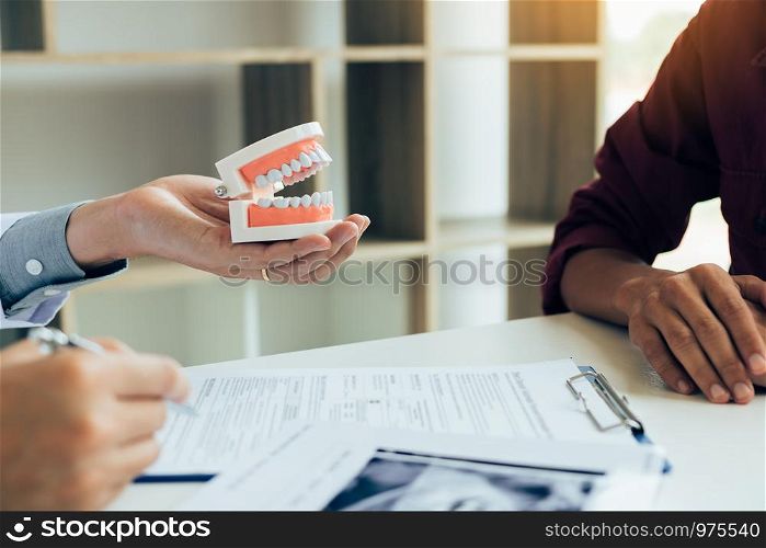 Asian male dentist hand holding pen writing patient history list on note pad.