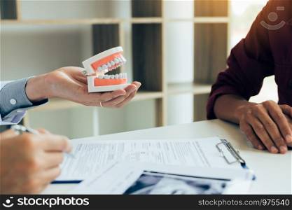 Asian male dentist hand holding pen writing patient history list on note pad.