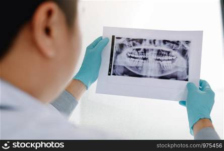 Asian male dentists are analyzing x-ray images of patients at the lab.
