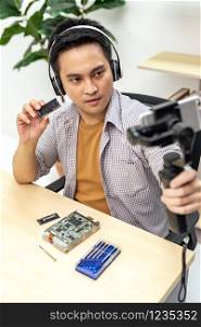 asian male IT vlogger and blogger live Technology upgrand on laptop memory ram using mobile phone recording live vlog video. Online influcencer on social media concept.