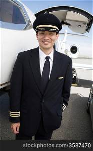 Asian male pilot in front of airplane, elevated view.