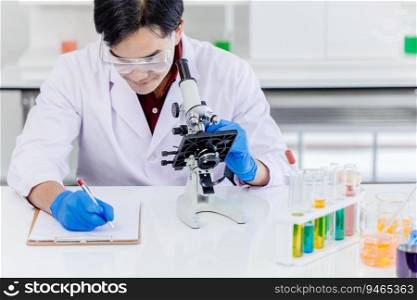 Asian male scientist working at laboratory desk with medical sample  record and microscope science equipment.
