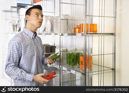 Asian male shopping for dishes and glasses in retail store.