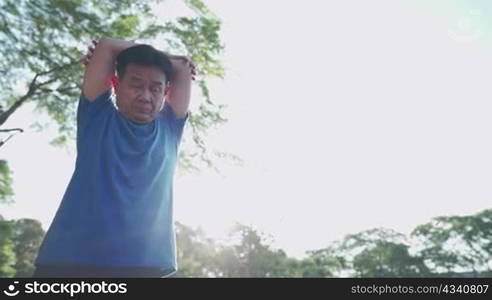 Asian male stretching arms and shoulders before exercise at the outdoor park, fresh air morning warm up exercise, active Motivation for retirement life, relieve and refreshing vibe, breathing control