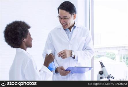 Asian male teacher is teaching science and experiment to African black boy in classroom at school. Education Concept.