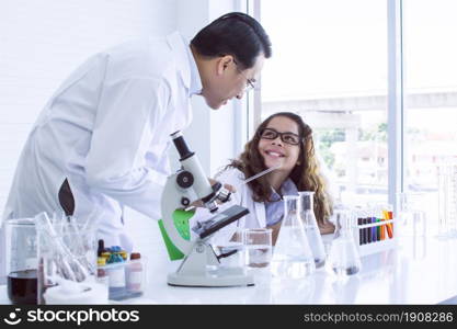 Asian male teacher is teaching science and experiment to caucasian teen girl in classroom at school. Education Concept.