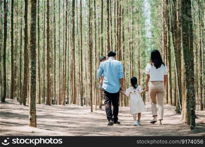 Asian man and a woman holding their baby and little kid walking through the forest on a sunny day, Happy family day