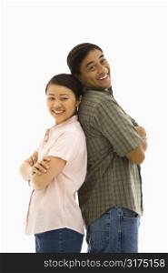 Asian man and woman standing back to back and smiling.