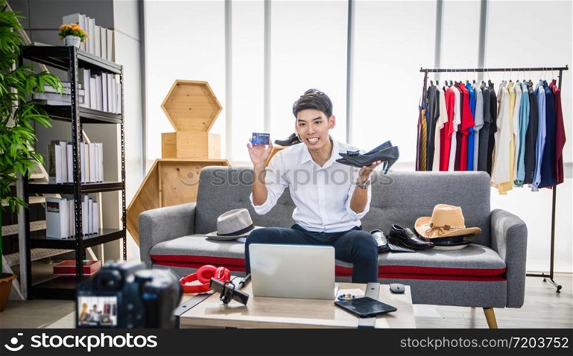 Asian man blogger broadcasting a video for selling product online such as Hats, shoes, headphones, clothing, safety headers.Shopping online concept at home