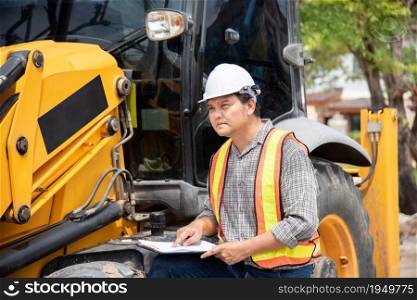 Asian man civil construction engineer worker or architect with helmet and safety vest working and holding a paper board note for see blueprints or plan at a building or construction site. Man construction engineer at construction site